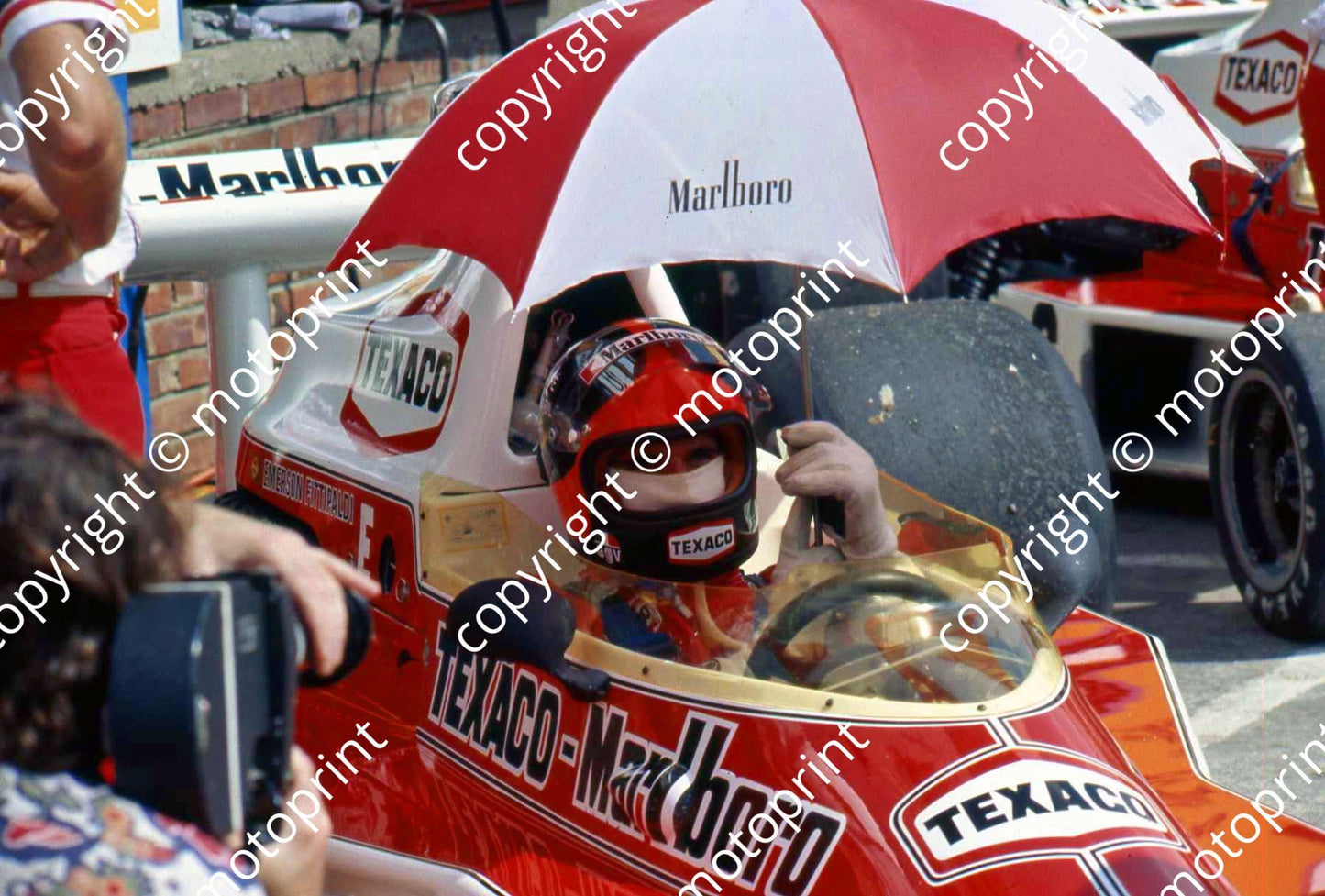 P E Fittipaldi under umbrella McLaren M23